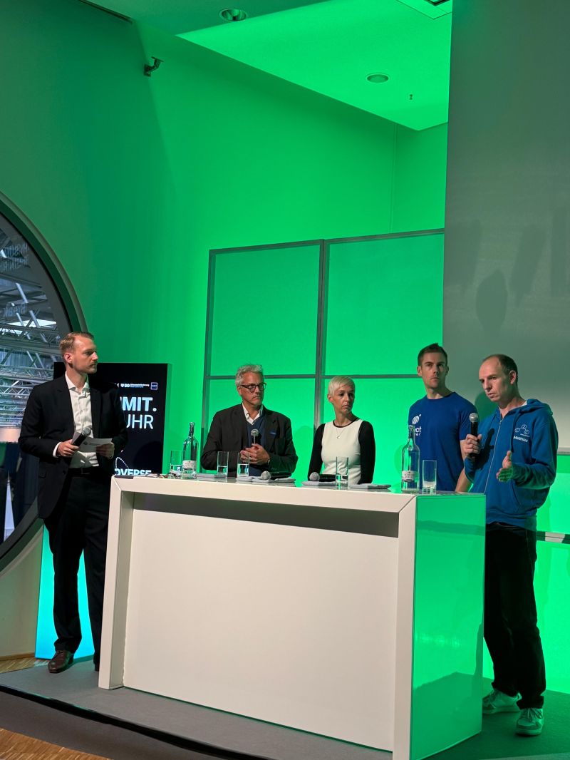 Podiumsdiskussion auf der grün beleuchteten Bühne des Hy.Summit.Rhein.Ruhr
